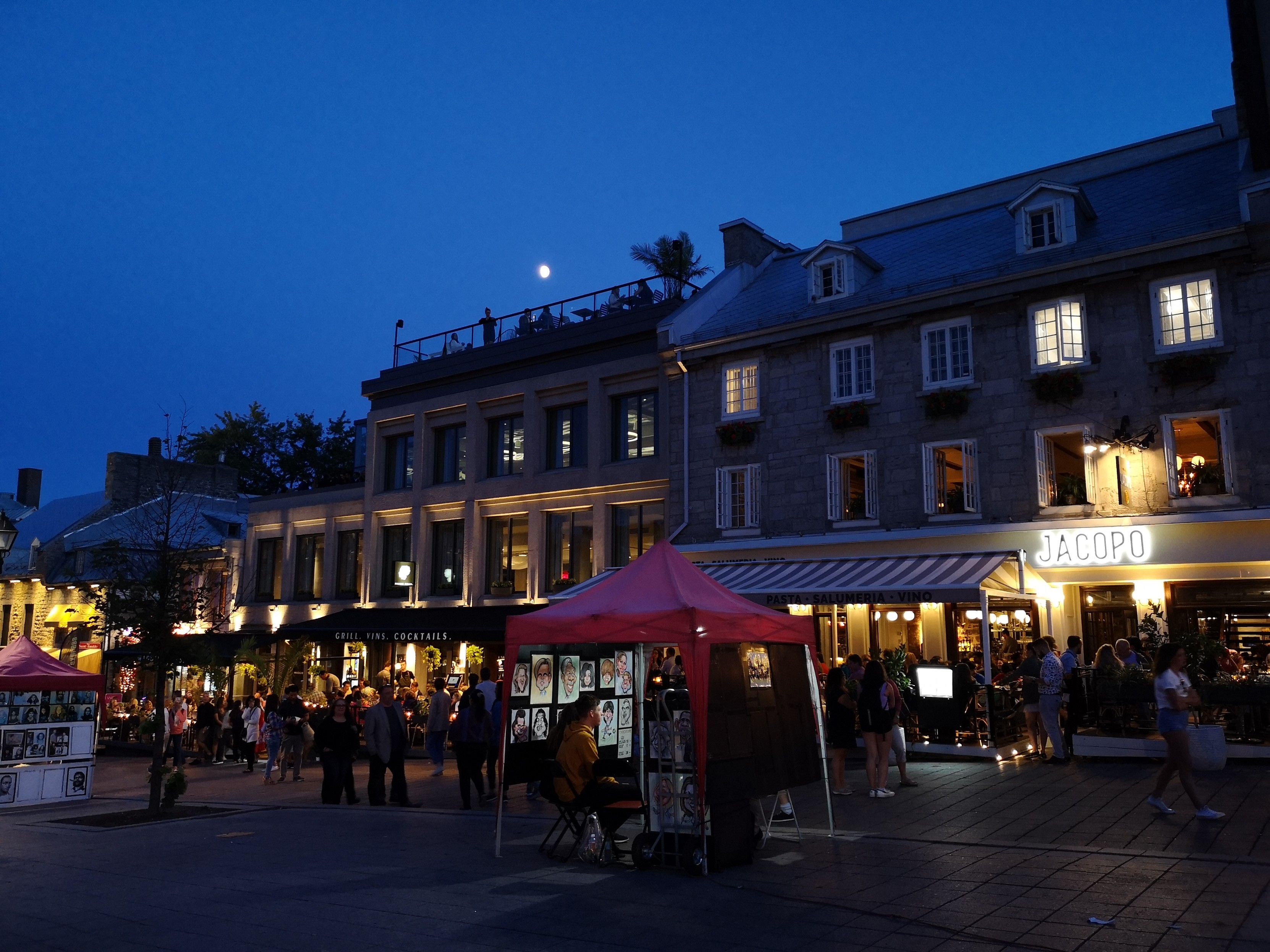 Abendlicher Straßenbetrieb in der blauen Stunde in Restaurants, Straßenmusiker, Künstler und Touristen sind unterwegs