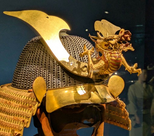 ein Helm einer feudalen Samurai Rüstung, auf dessen Vorderseite ein Drachen angebracht ist