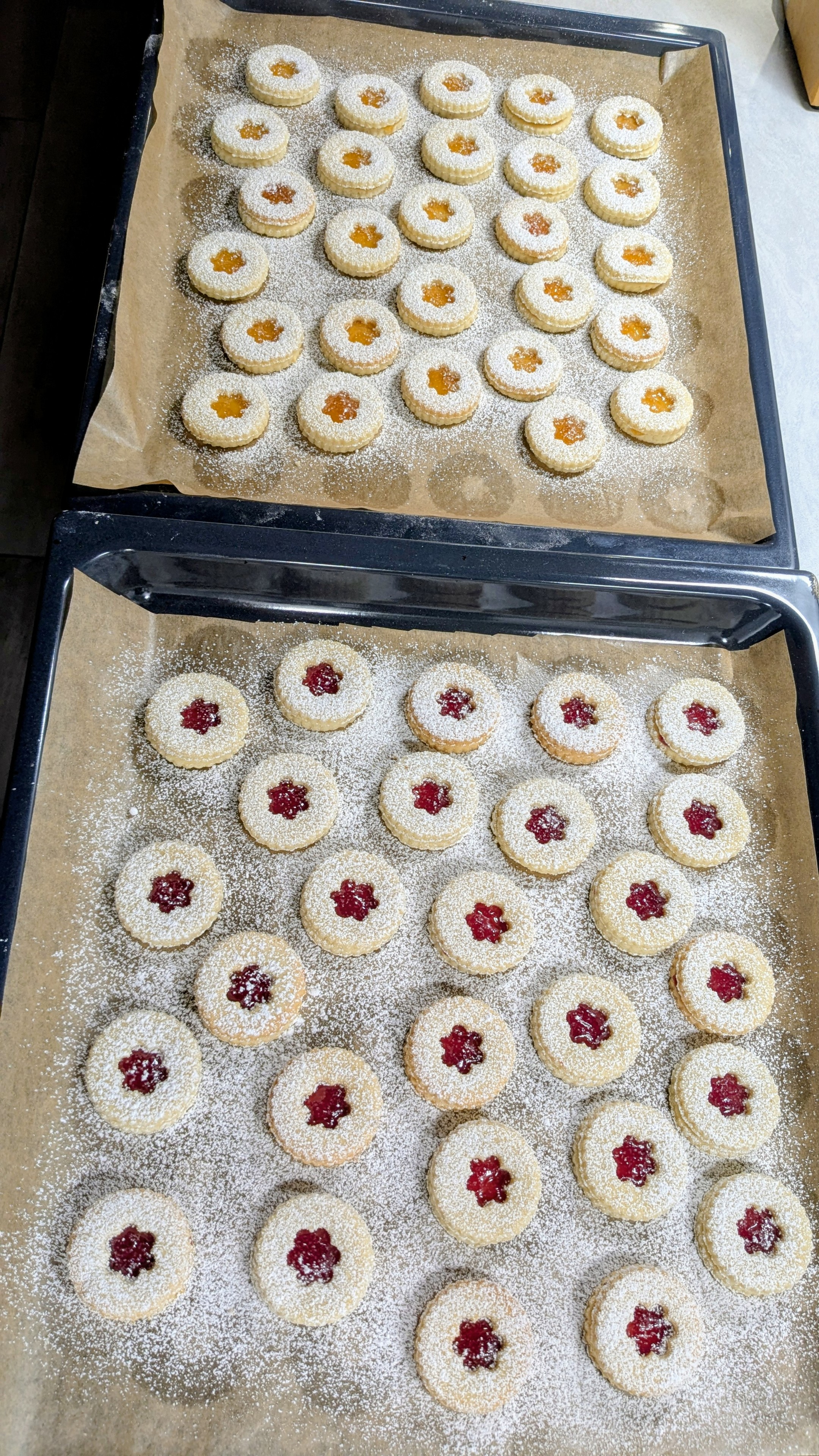 2 Bleche mit Spitzbuben. Eine Hälfte mit Aprikosenkonfitüre, die andere Hälfte mit Himbeergelee