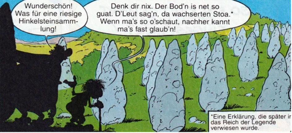 Der Gallier Appendix und Obelix stehen im Vordergrund. Im Hintergrund sind viele Hinkelsteine auf einer Wiese zu sehen.