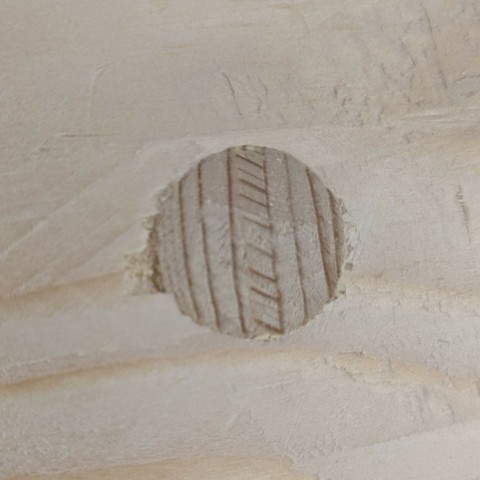 in einer Holzfläche ist ein runder Stab, mit dem eingeschlagenen Keil, plan abgeschnitten