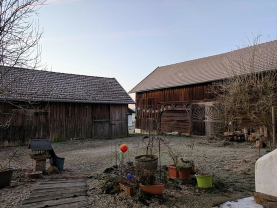 Blick auf eine kleine und große Holzscheune, deren Dächer von Reif bedeckt sind