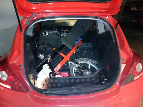 offener Kofferraum eines kleinen roten Autos, in dem der Vorderteil eines Liegeradtandems liegt