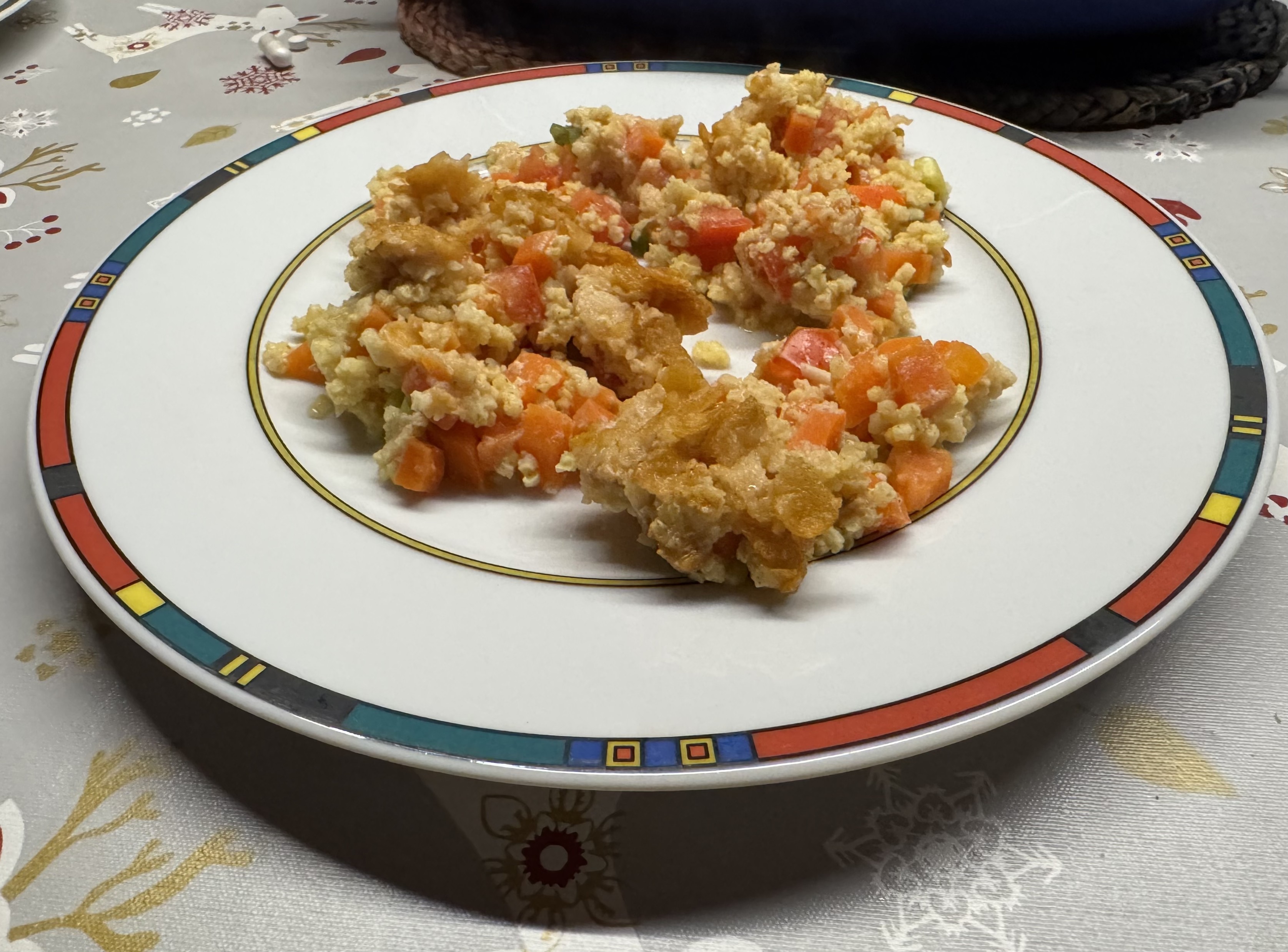 Eine Portion des Auflaufs auf einem Teller mit buntem Randdekor.
