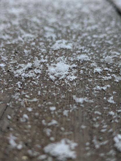 einzelne große Schneeflocken auf einer Holzterrasse