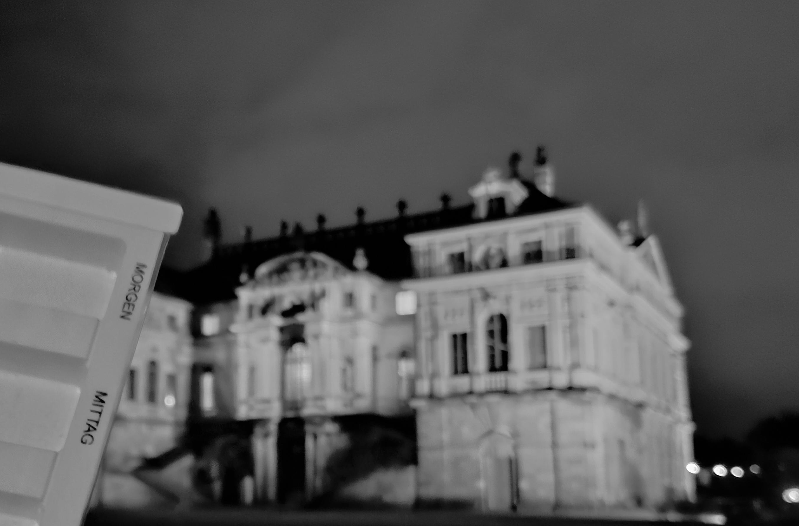 Links im Bild ist eine Tablettendose, im Hintergrund das Palais im Dresdener Großen Garten bei Nacht.