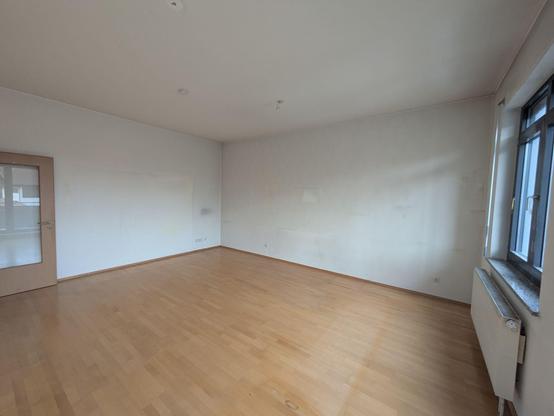 ein leeres Zimmer mit ein paar Verfärbungen an Wand und Boden von ehemals dort gewesenen Möbeln und Bildern