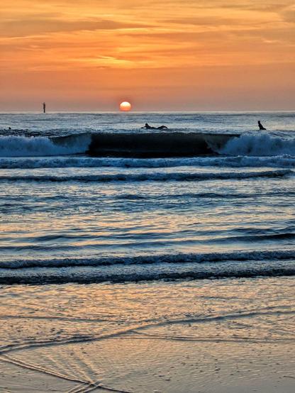 Sonnenuntergang über das Meer fotografiert. Ein paar Surfer paddeln