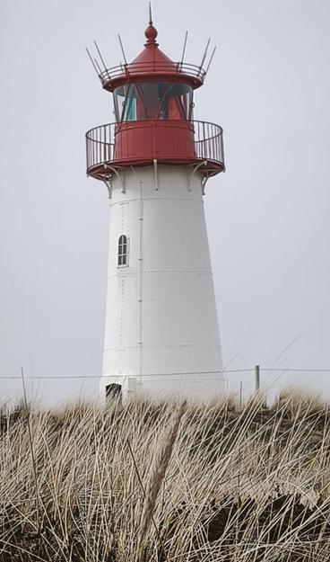ein rotweißer Leuchtturm vor grauem Himmel