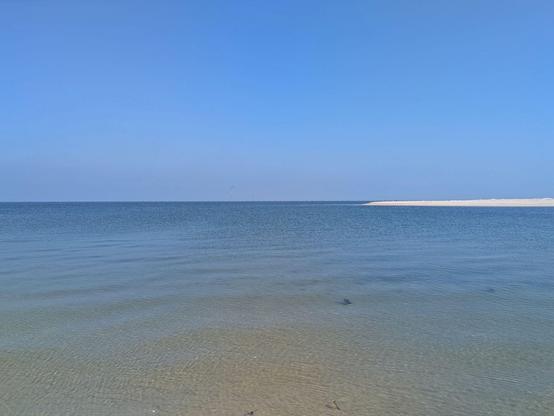 blauer Himmel nblaues Wasser und am rechten Rand heller Sand