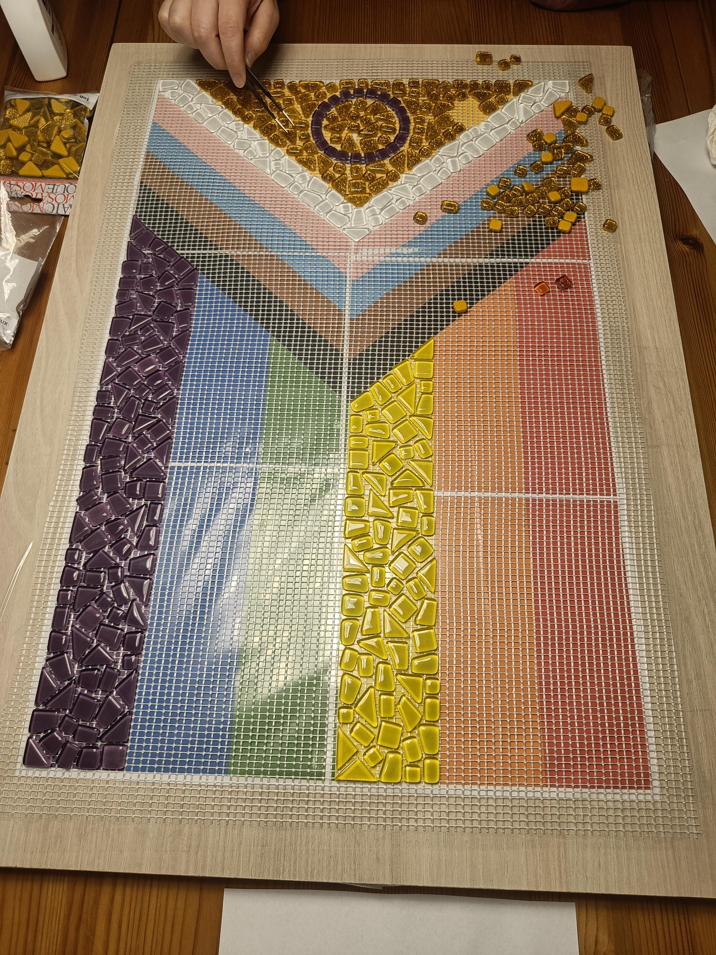 Pride Flag Mosaik in Arbeit. Goldener Glitzer wird verlegt.
