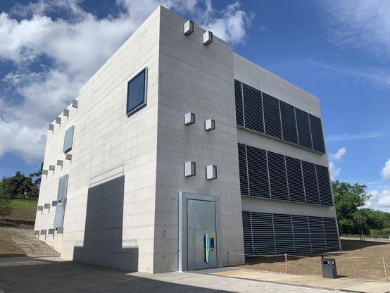 Offenbar das neue Rechenzentrum - ein einzelnen Fenster, ansonsten nur grosse Lüftungsöffnungen auf Sichtbeton, dazu regelmässig angeordnete Nistkästen.