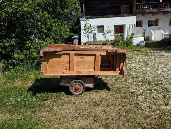 ein altes Unterteil, ca 2 m lang, liegt flach auf einem kleinen geschweißten Handkarren, der viel kürzer als der Schrank ist.