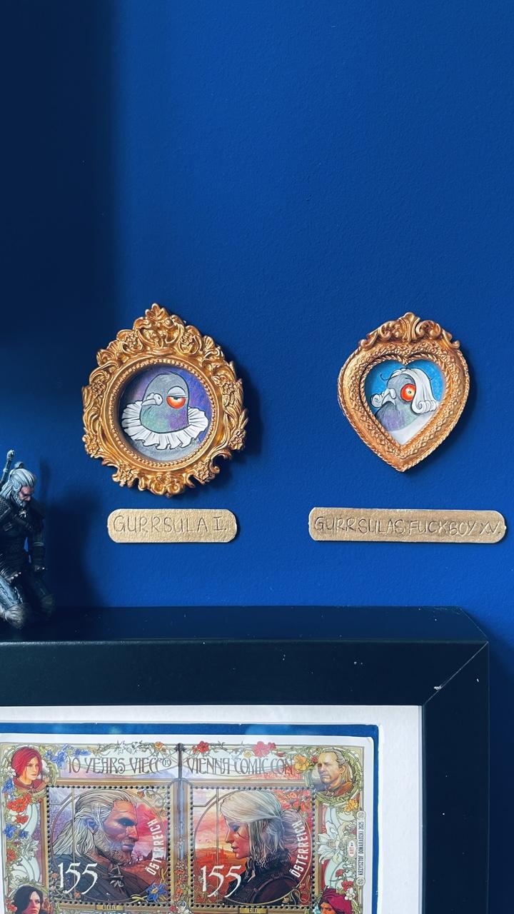 Die beiden Tauben Portraits in ihren güldenen Rahmen hängen jetzt beide nebeneinander an der blauen Wand, sie haben vergoldete Namensschilder darunter. Eine Miniaturfigur vom Hexer Geralt von Riva steht direkt daneben in kniender Pose unter Gurrsula, wie es sich gebührt.