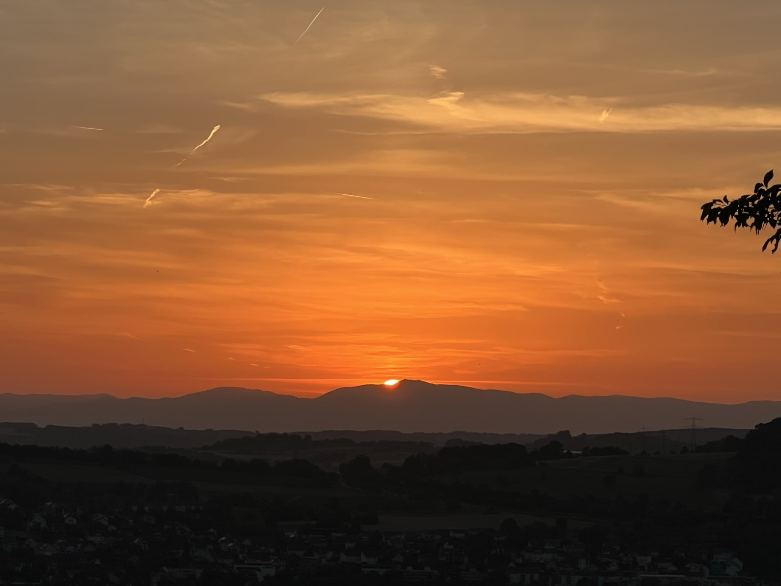 Nur ein Stück der Sonne am roten Abendhimmel schaut noch hinter dem Berg hervor