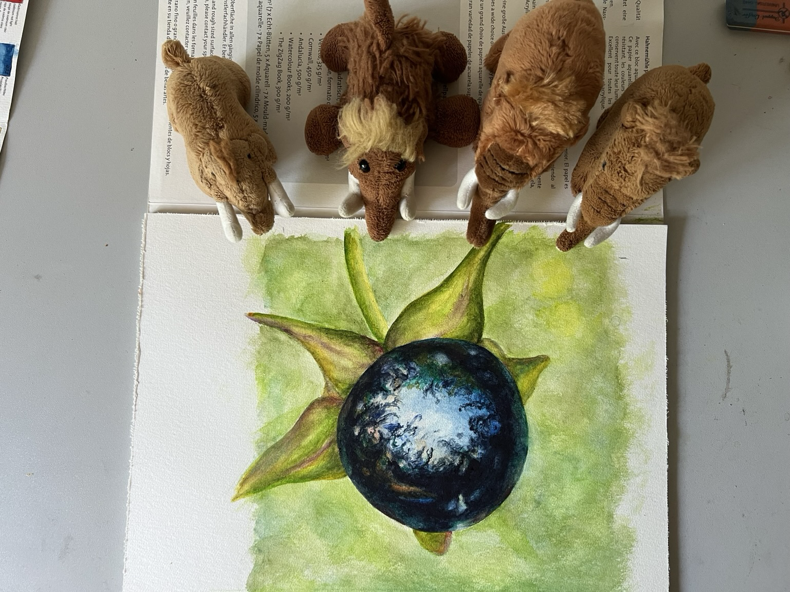 Die vier plüschigen Mammuts mit dem Aquarell Bild. Der Wald spiegelt sich auf der Tollkirsche.