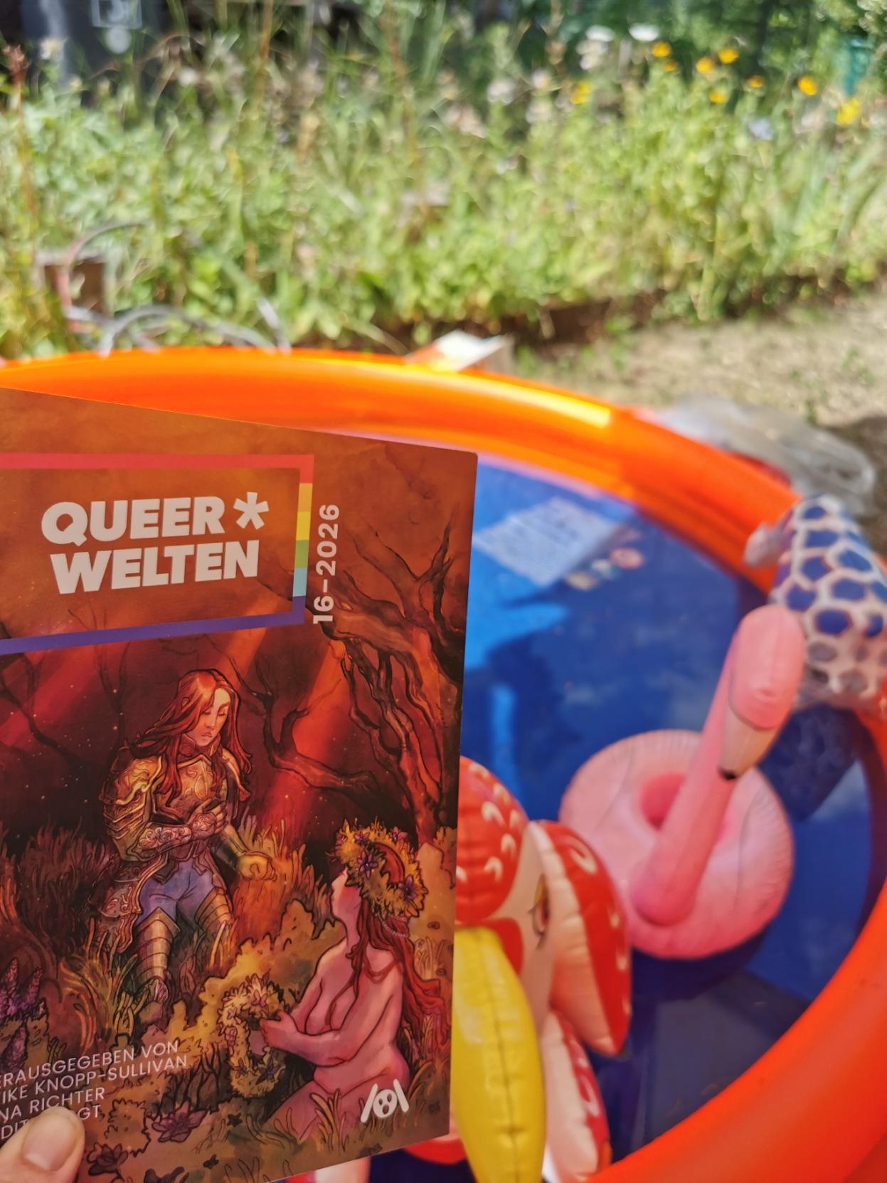 Ein Buch mit Titel Queerwelten, dahinter unscharf ein Planschbecken mit Badetieren und ein grünes Beet