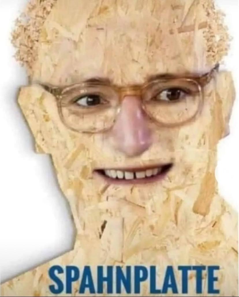 Porträt eines Gesichts mit Brille, das aus Holzspänen zusammengesetzt ist, darunter der Schriftzug 'SPAHNPLATTE'