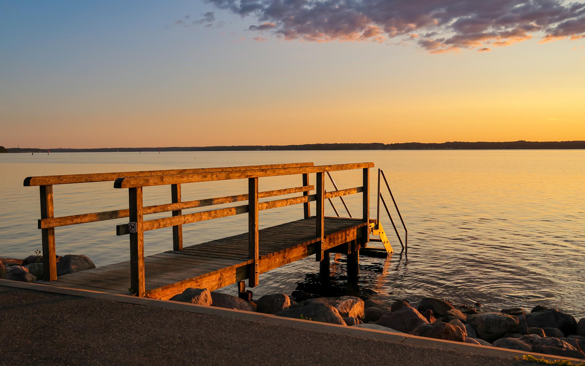 Ein Badesteg am Wasser
Von der Abendsonne vergoldet, über dem Wasser verfärbt sich der Himmel gelb
