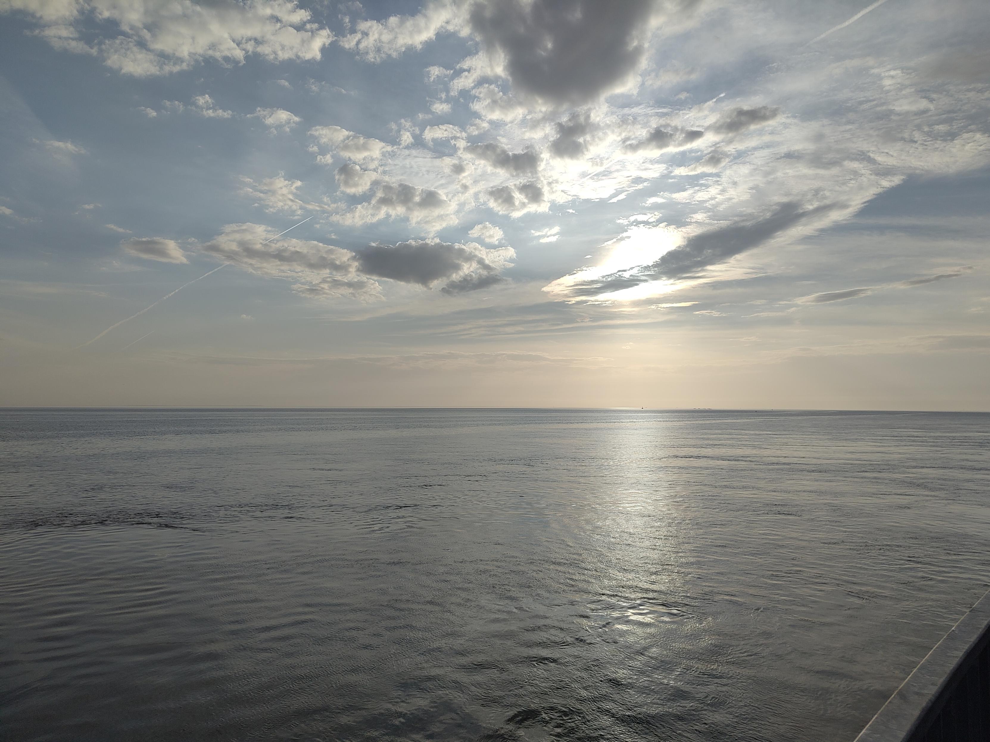 Ein Bild von der Nordsee, in Büsum aufgenommen. Blick aufs Meer, die Sonne scheint durch die Wolken.