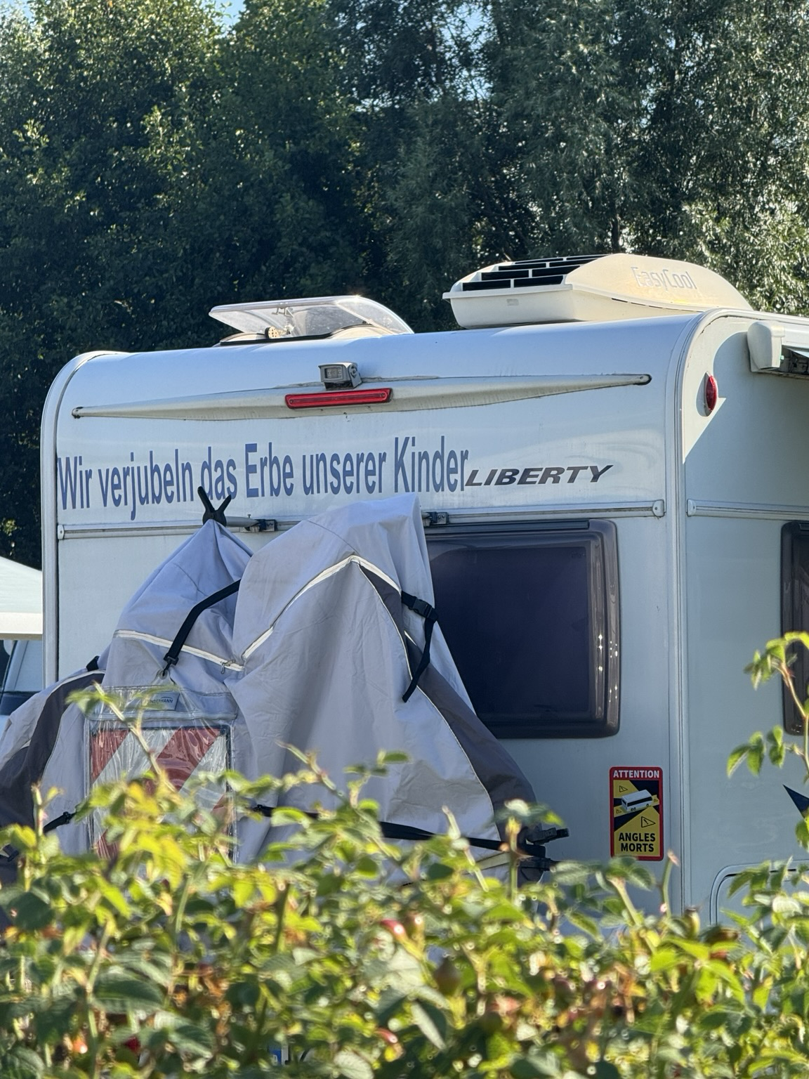 Wohnmobil von hinten, auf dem oberen Teil der Spruch: „Wir verjubeln das Erbe unserer Kinder“