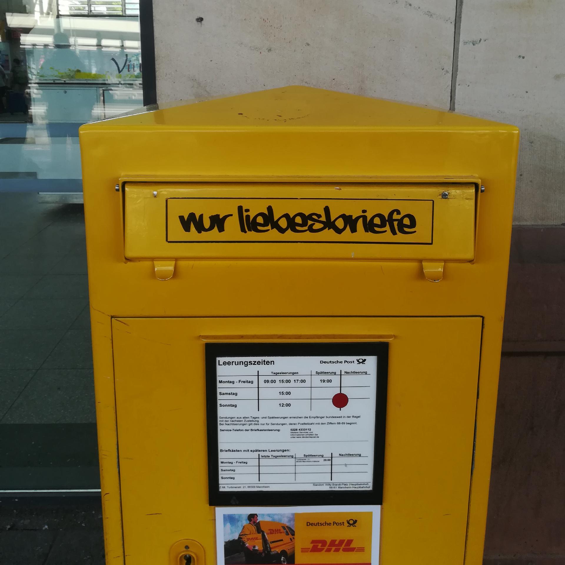 Ein gelber Briefkasten der deutschen Post mit dem Graffiti "nur Liebesbriefe"