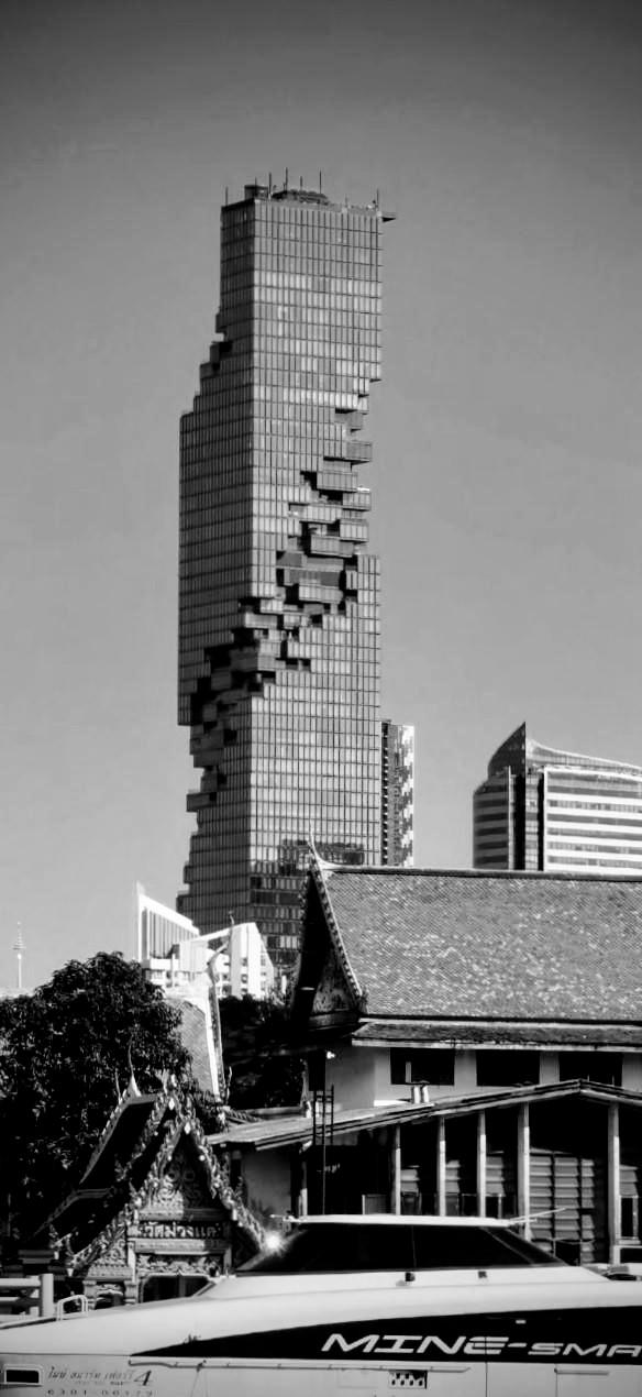 Im Mittelpunkt ein hoher Turm, dessen Glasfassade aussieht, als würde er zerbrechen. An allen Außenseiten sind rund herum Lücken, Aussparungen gelassen worden, so dass von Weitem der Eindruck entsteht, er hätte Risse und würde zusammenfallen. 
Vorne im Bild das Dach eines Schnellbootes, dahinter traditionell asiatische Spitzdächer.