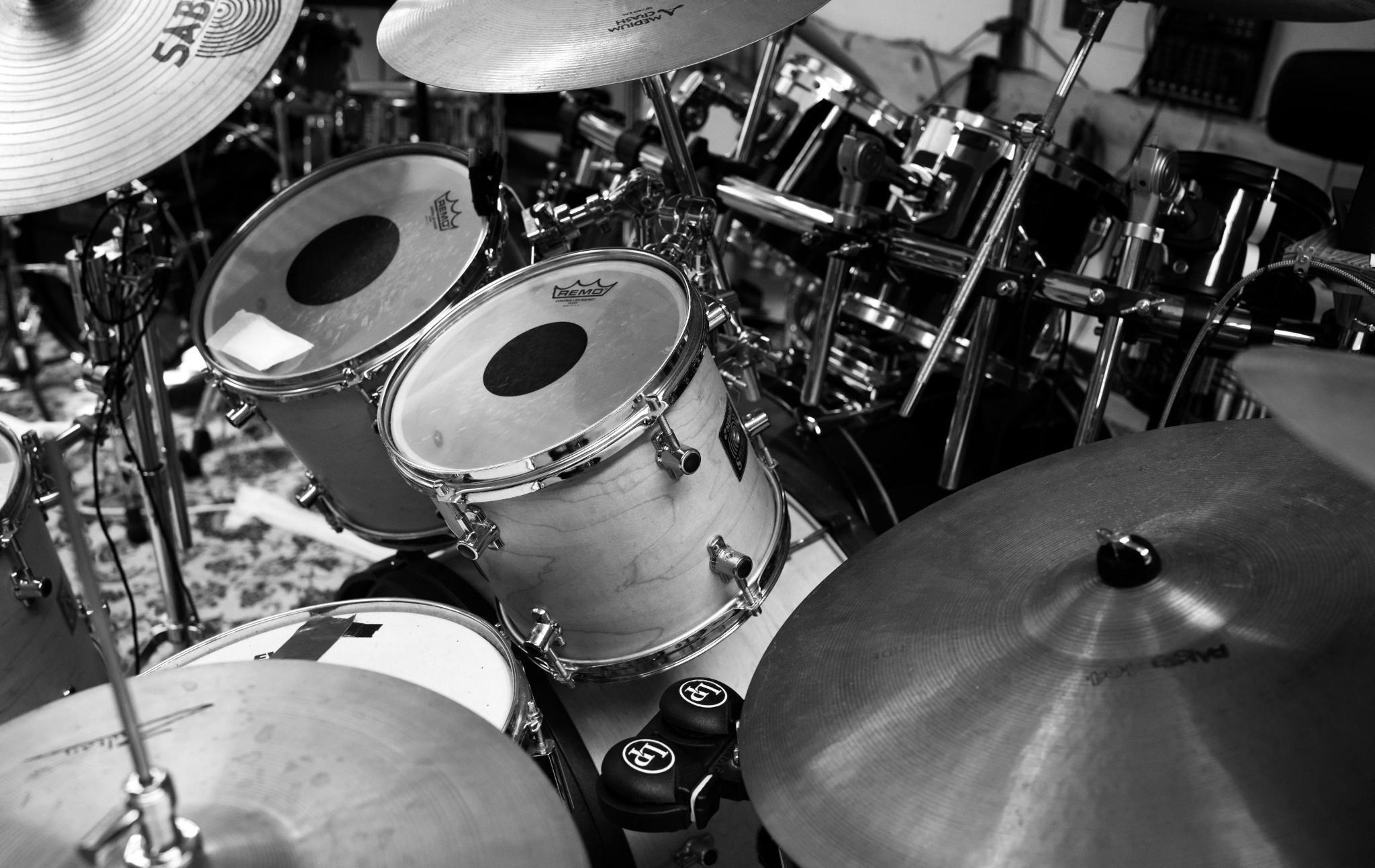 Schwarzweiß Foto: Ein Schlagzeug, zwei drums in der Bildmitte und Becken und anderes Schlagwerk drumherum, die das Bild komplex aussehen lassen.